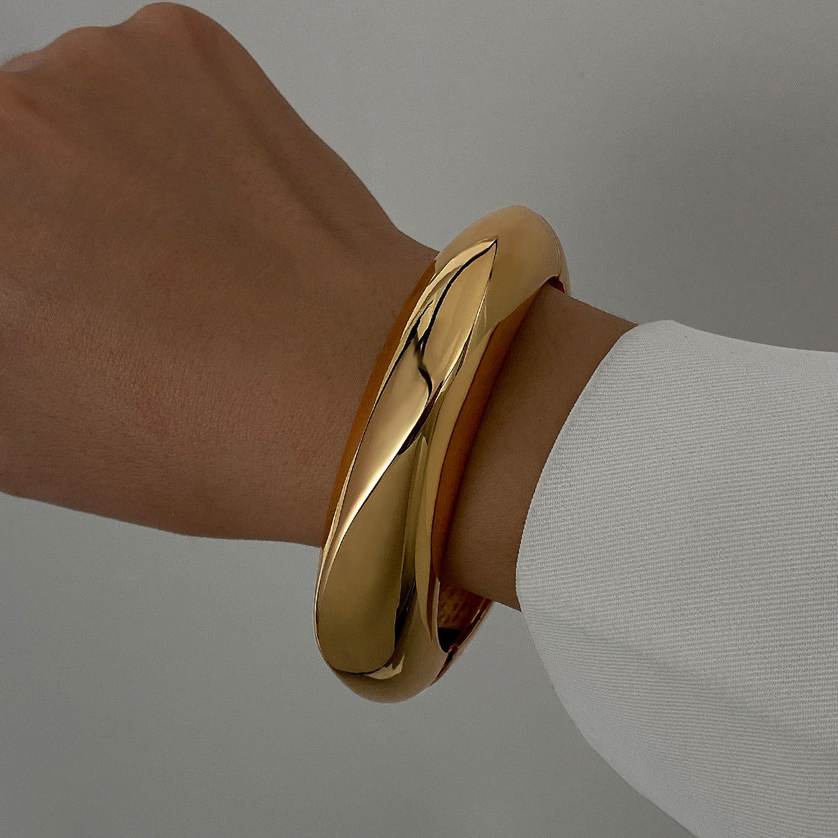Polished Gold-Tone Bangle Bracelet with Elegant Curve
